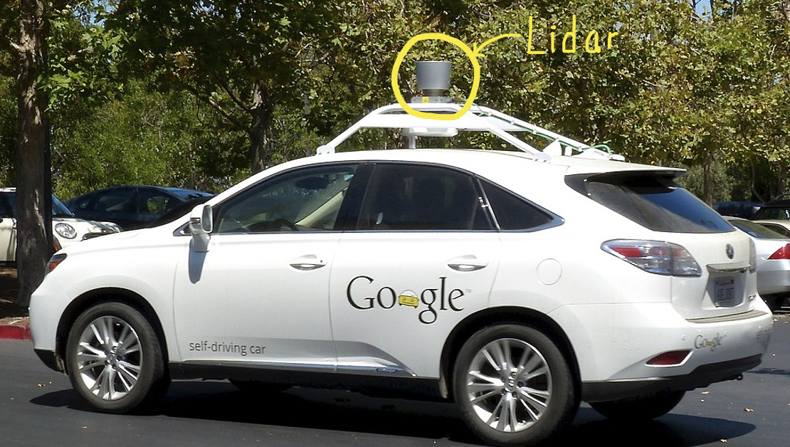 picture of a waymo Lexus SUV, white, with a Lidar unit on top. The Lidar is a gray cylinder about 8 inches tall and a 4 inch radius